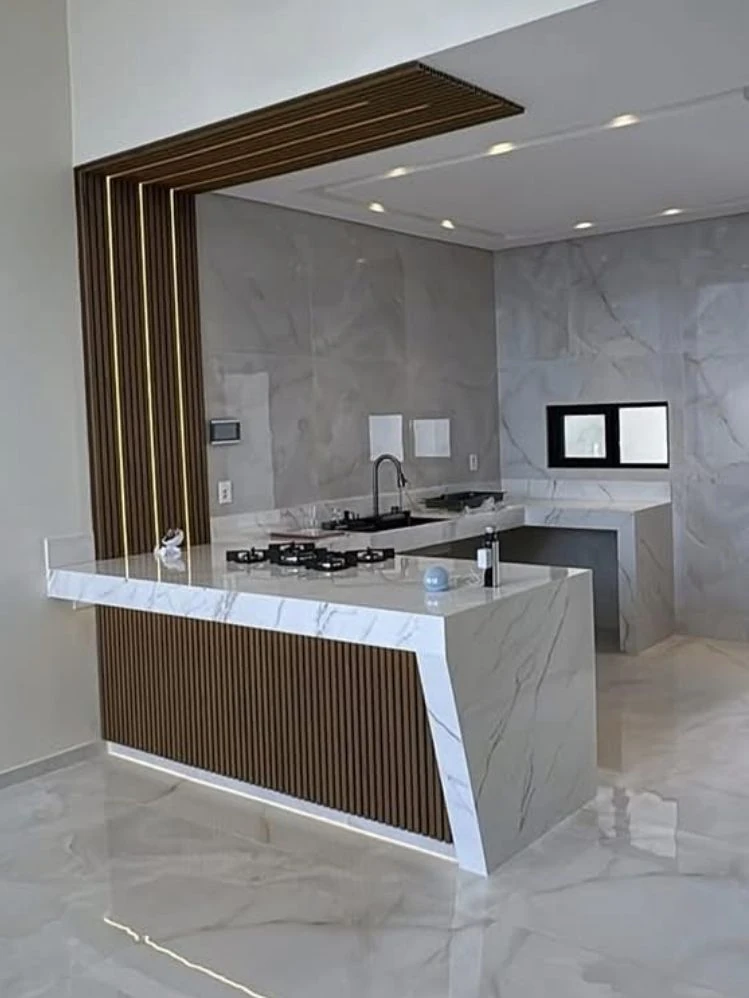 Cozinha branca com ilha revestida em pedra clara e detalhes amadeirados