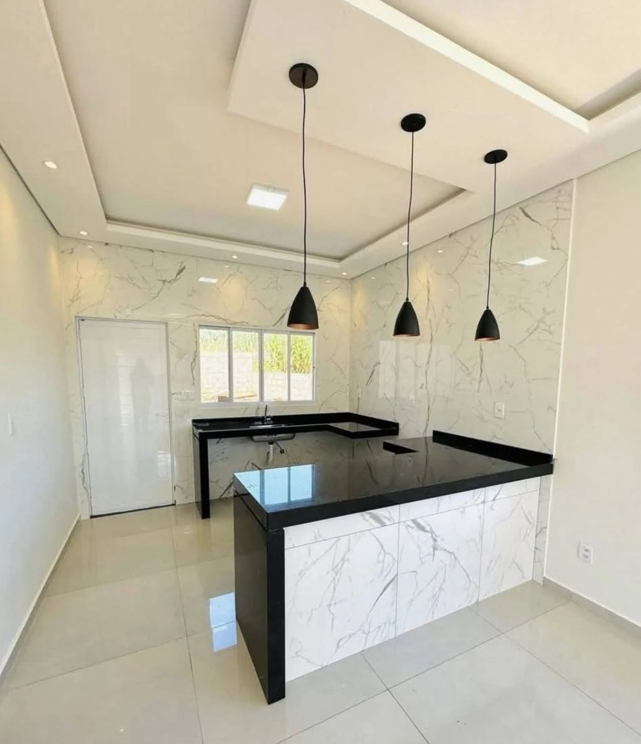 Cozinha contemporânea com bancadas pretas e paredes com veios de mármore